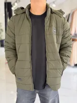 Campera puffer azul marino con capucha ajustable, cierre frontal y bolsillos laterales con cierre a presión. Cuenta con parche redondo con la inscripción "TURK" en el pecho.