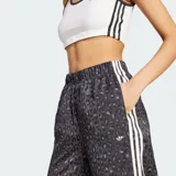 Pantalón Adidas de pierna ancha, estilo wide leg, con estampado animal print en tonos grises y negros. Presenta cintura elástica fruncida y las icónicas tres tiras blancas laterales a lo largo de cada pierna con el logo del Trifolio bordado.