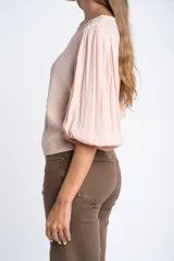 Blusa color rosa pálido, de manga larga abullonada con puño elástico y escote redondo.