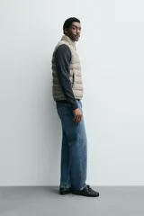 Chaleco acolchado verde oscuro, con cuello alto, cierre frontal con cremallera y bolsillos laterales. Confeccionado en tejido técnico repelente al agua.