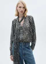 Blusa de manga larga abullonada con estampado de leopardo en tonos grises y negros. Presenta cuello redondo con cierre de lazo.