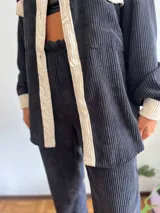 Pantalón de pana negro con bolsillos traseros de pana color crema y cintura elastizada.