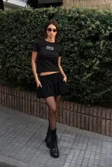 Minifalda negra de corte evasé con pretina elástica, bolsillos laterales y bolsillo trasero.