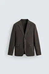 Blazer de corte relajado confeccionada en mezcla de algodón con acabado efecto lavado. Presenta cuello con solapas de muesca, cierre frontal con dos botones, bolsillo de vivo en el pecho y bolsillos con solapa en la cadera. Diseño sin forro interior con aberturas en la espalda.