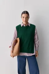 Chaleco tejido de punto color beige, con cuello redondo, terminaciones en rib y lazos laterales regulables que permiten ajustar la prenda.