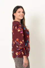 Blusa color borgoña con estampado de flores multicolores, escote en V con botones forrados, mangas largas con frunces en los puños y hombros.