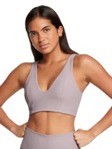 Top deportivo Under Armour Meridian Rib Bralette de color lila, confeccionado en tejido acanalado de punto con escote en V profundo y diseño alargado.