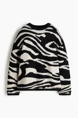 Buzo oversized en punto jacquard con estampado de cebra, cuello redondo y hombros caídos. Presenta terminaciones acanaladas en el cuello, puños y bajo.