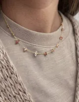 Collar de cadena dorada fina con pequeñas piedras naturales engarzadas en tonos rosados, ámbar y cristalino.