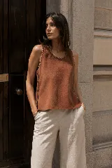 Top sin mangas confeccionado en cuero natural color tostado, con silueta recta, cuello redondo y costuras decorativas visibles. Presenta detalles metálicos en los laterales.