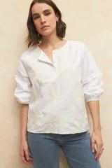 Blusa blanca de algodón bordada, de manga larga con cuello mao y mangas abullonadas con elástico en los puños.