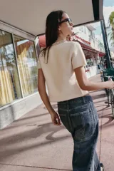 Chaqueta de punto de lana con manga corta, cuello redondo decorado con abalorios joya y cierre frontal con botones forrados a tono.