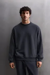 Sudadera negra de entrenamiento relaxed fit confeccionada en tejido de algodón con interior rizo, cuello redondo, manga larga y acabados en rib.