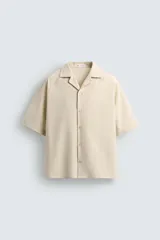 Camisa de corte boxy fit confeccionada en tejido con algodón, con cuello bowling y manga corta. Presenta cierre frontal con botones.