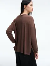 Sweater de punto amplio con sutiles micro lentejuelas integradas al tejido. Presenta cuello redondo relajado, hombros caídos y mangas largas con puños ajustados. Su diseño cuenta con un largo generoso y aberturas laterales en el ruedo.