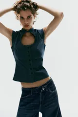 Top entallado de efecto denim, con cuello subido, manga corta, cierre frontal con botones y una llamativa abertura circular en el pecho.