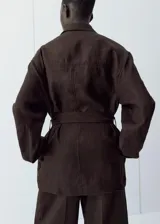 Chaqueta de lino color marrón, de diseño recto, manga larga, cuello camisero, cierre frontal de botones y cinturón ajustable del mismo tejido.