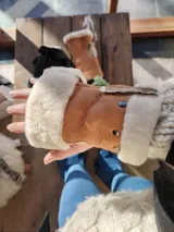 Mitones de cuero color marrón con borde de corderito blanco.