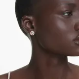 Par de aros Swarovski Dextera con baño de oro rosa. Cada aro tiene un diseño circular con una mitad cubierta de cristales transparentes y una zirconia central móvil.