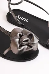 Sandalias bajas color cuero con tiras finas y aplique de flor dorada.