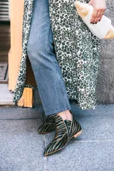 Botines de piel con diseño original, confeccionados artesanalmente en España. Presentan un estampado animal print en tonos verde y negro, con una estructura de piezas superpuestas y una pieza frontal elevada que estiliza el empeine. Cuentan con cierre lateral, interior forrado en piel y suela de cuero.
