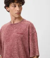 Remera masculina oversized de algodón con acabado desteñido y lavado desgastado de estilo vintage. Presenta cuello redondo de canalé y un pequeño bordado en el pecho con relieve.