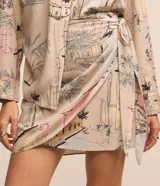 Pollera recta corta de viscosa en color beige con estampado de paisajes y palmeras, con lazo lateral ajustable en la cintura.