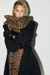 Bufanda de tejido suave y cepillado con estampado de leopardo en tonos marrón y negro. Presenta flecos largos en los bordes.