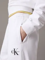 Pantalón de jogging blanco de felpa de mezcla de algodón, con cintura elástica con cordón ajustable, bolsillos laterales, bajos de canalé y monograma CK en la pierna. Corte tapered y largo estándar.