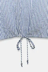 Camisa de cuello solapa y manga larga a rayas azules y blancas, con bajo ajustable mediante cordones y cierre frontal con botones ocultos.