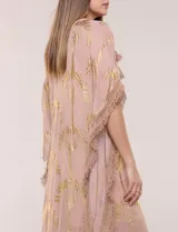 Vestido midi tipo túnica de silueta holgada, marca America & Beyond, color rosado con estampado metalizado dorado de palmeras. Cuenta con escote en V, detalles de borlas, espejos y apliques decorativos, y flecos en mangas, laterales y ruedo.