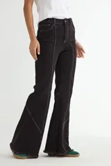 Jean de corte flare en color negro, con costuras verticales decorativas en contraste y ruedo deshilachado.