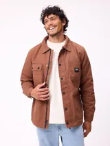 Sobrecamisa de algodón color marrón, con cierre frontal de cremallera y botones a presión. Presenta cuello clásico, dos bolsillos frontales con solapa y cierre de botón, y forro interior de poliéster.