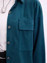 Campera de pana negra con cierre frontal de botones metálicos, cuello clásico y dos bolsillos frontales con solapa. Presenta mangas largas con puños abotonados y un diseño liviano sin forro.