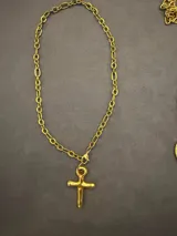 Collar de cadena de eslabones dorados con dije de cruz de diseño orgánico y acabado brillante.