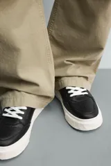 Zapatilla deportiva de estilo retro con parte superior de cuero sintético y suela de plataforma con diseño irregular y texturizado.