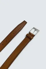 Cinturón de piel color marrón con costuras decorativas en los bordes. Presenta una hebilla metálica rectangular de color plateado y un pasador a juego.