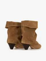 Bota de gamuza color marrón claro con caña media, punta fina y taco geométrico de madera color negro. El borde superior de la bota está doblado hacia afuera.