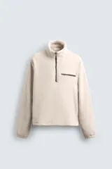 Sudadera de tejido polar con textura efecto pelo, corte relajado, cuello subido con cierre frontal de cremallera, manga larga con puños elásticos y bolsillo con cierre en el pecho.