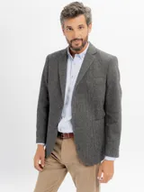 Saco de paño gris de corte regular fit, con cuello de solapa clásica, bolsillos frontales con solapa, bolsillo ojal en el pecho y cierre de dos botones.