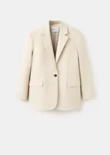 Blazer Paola de corte recto, color beige, confeccionado en mezcla de lana y lino. Presenta cuello pico con solapa, mangas largas, un bolsillo de ribete en el pecho, dos bolsillos con solapa en los laterales y cierre frontal de un botón oscuro.