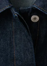 Chaqueta corta de denim en color azul oscuro, con cuello clásico, cierre frontal con botones, mangas largas y un bolsillo aplicado en el pecho.