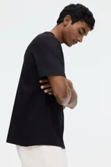 Remera de punto liviano color negro, con cuello redondo ribeteado, mangas cortas y bajo recto. Corte estándar y silueta clásica.