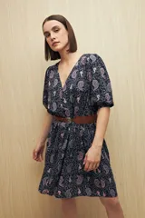 Vestido corto con estampado paisley en tonos azul marino, rosa y blanco. Tiene escote en V, mangas cortas abullonadas con puños elásticos, corte en la cintura y falda con vuelo. Incluye cinturón marrón.