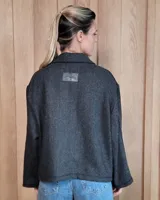 Chaqueta de textura bouclé en color bordó, con corte oversize, cuello camisero, cierre frontal y bolsillos laterales.