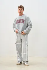 Pantalón de jogging gris melange de corte ancho, con bolsillos laterales y detalles de costuras blancas a contraste.