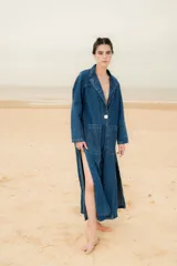 Tapado largo de denim con bolsillos delanteros, solapa clásica, cierre de un botón y aberturas laterales pronunciadas.