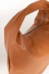 Bolso negro tipo hobo de cuero sintético, con asa corta fija y cierre superior.