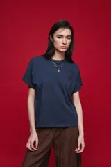 Remera negra de manga corta con cuello redondo y silueta amplia, de hombros caídos y textura suave.