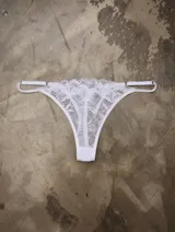 Tanga confeccionada en puntilla blanca con tiras laterales regulables.